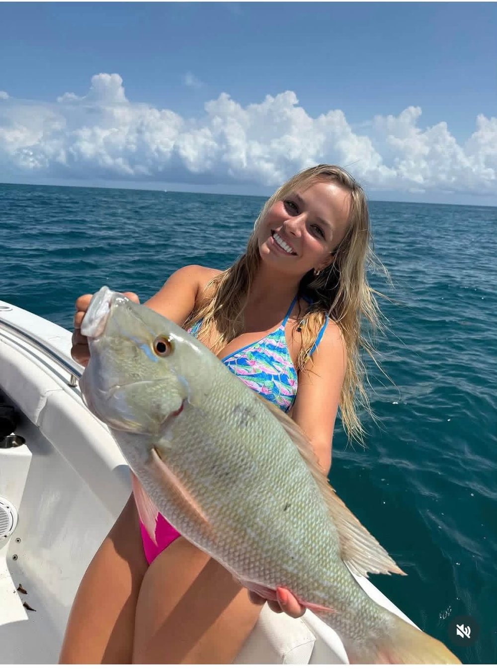 Lauryn Akey smiling on a boat, holding a big fish she caught