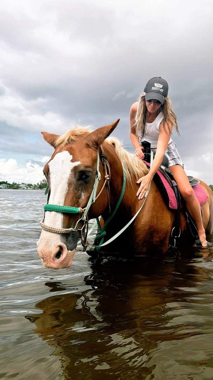Kendra on a chestnut horse standing in shallow water