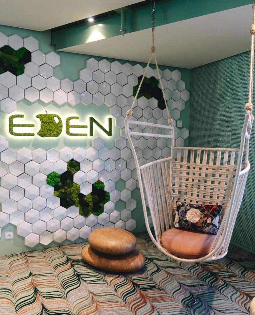 The Eden sign above a hanging chair in a mint-green lounge