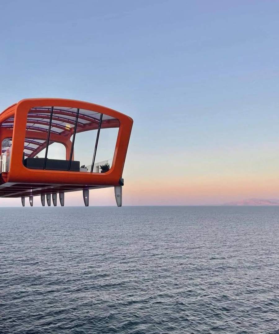 The orange Magic Carpet platform extended over the ocean at dusk