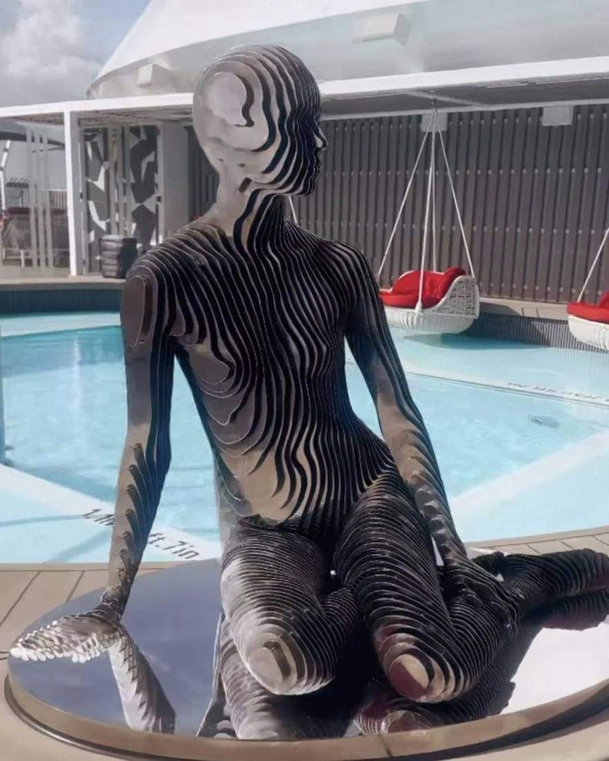 A mirrored sculpture sitting by a pool