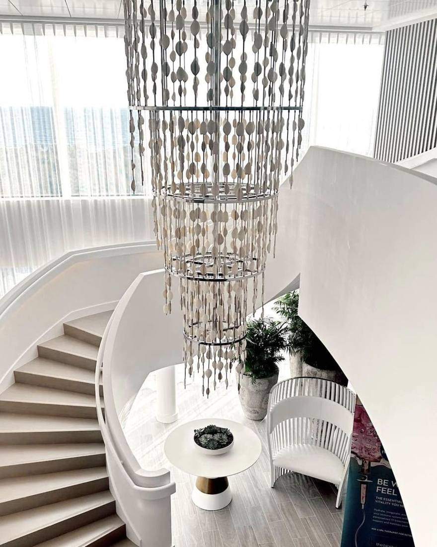 A shell-style chandelier above a white spiral staircase