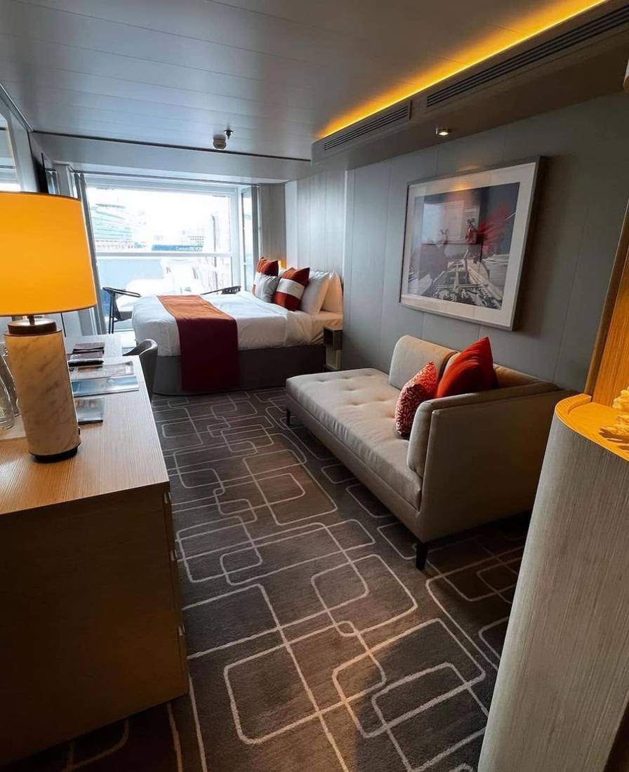 A stateroom with a bed, sofa and balcony doors