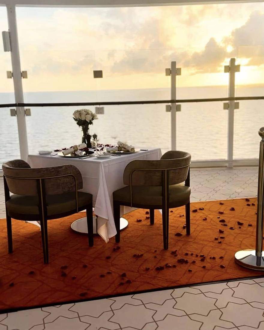 A table for two at sunset with rose petals on the carpet