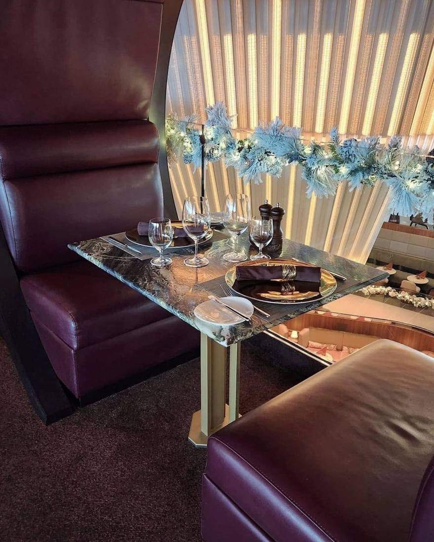 A dining table set for two beside a holiday garland