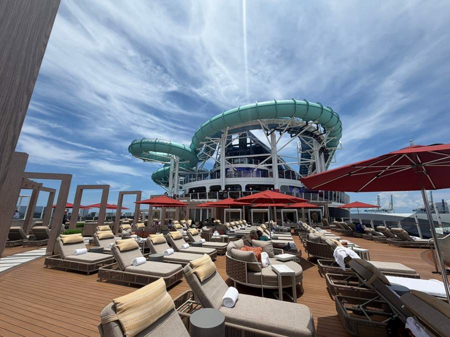 Lounge chairs on the pool deck with waterslides rising above
