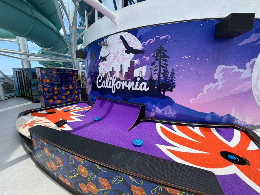 A California-themed mini golf hole with a purple ramp and mural