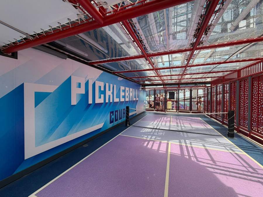 The pickleball court with a blue painted wall and red steel frame