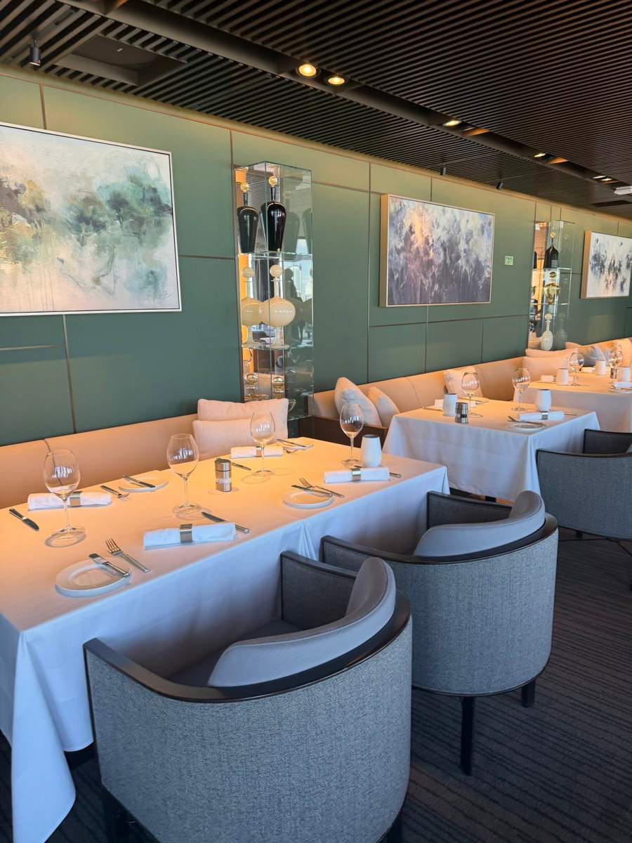 A restaurant with set tables and a green wall with artwork